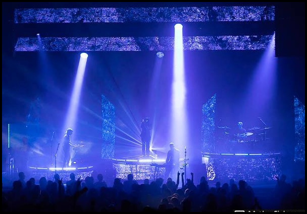 Concert stage with dramatic purple and blue beam lighting